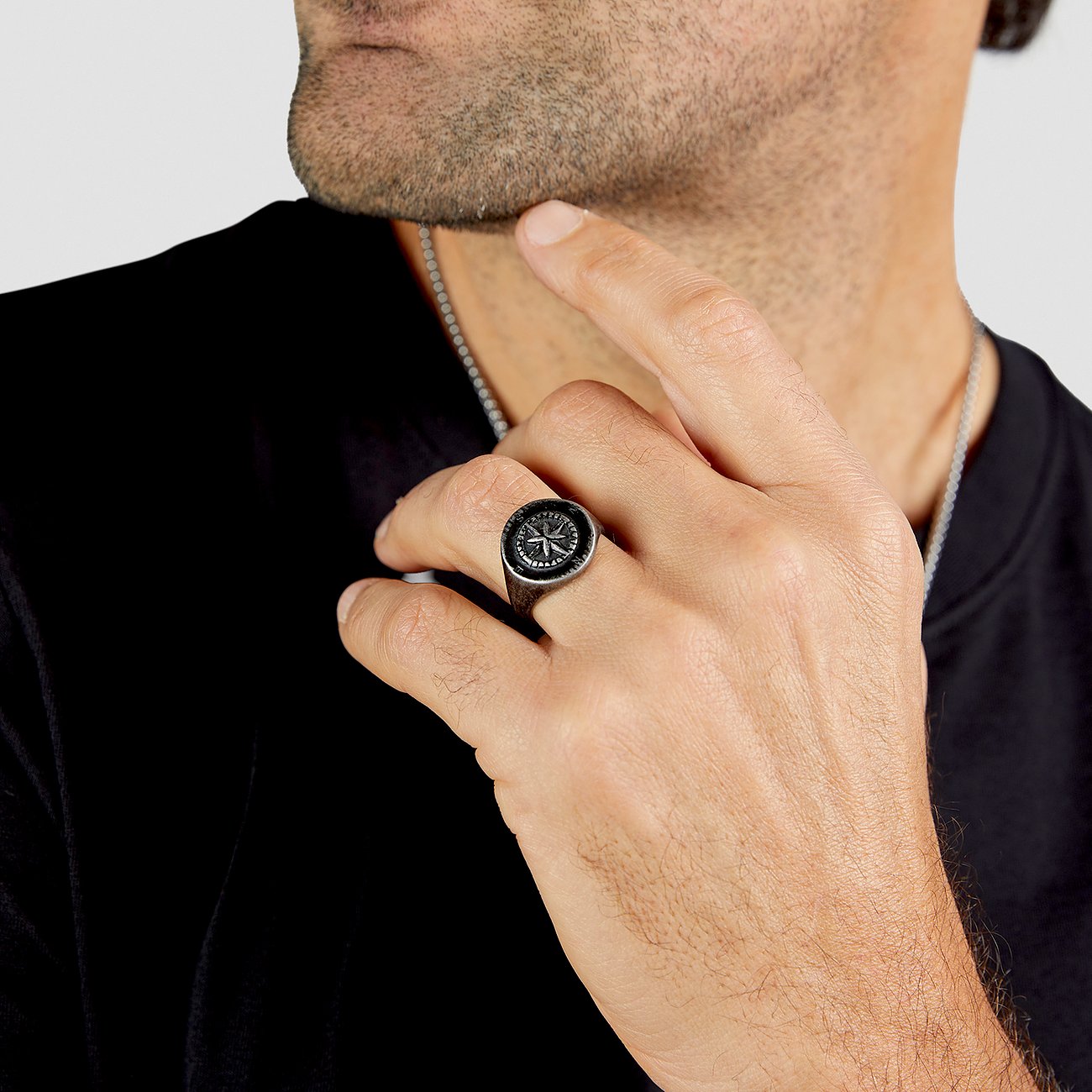 Ein Mann trägt einen s.Oliver Edelstahlring mit einem Kompassmotiv auf dem rechten Ringfinger. Nahaufnahme.