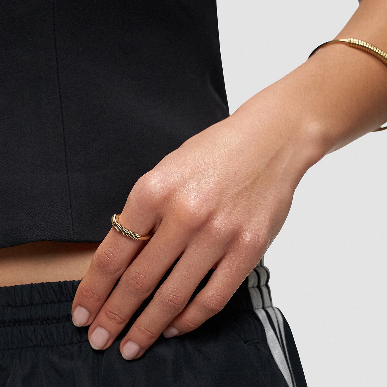 Nærbillede af en guld Liebeskind rustfri stålring med rillet design foran, båret på en finger.