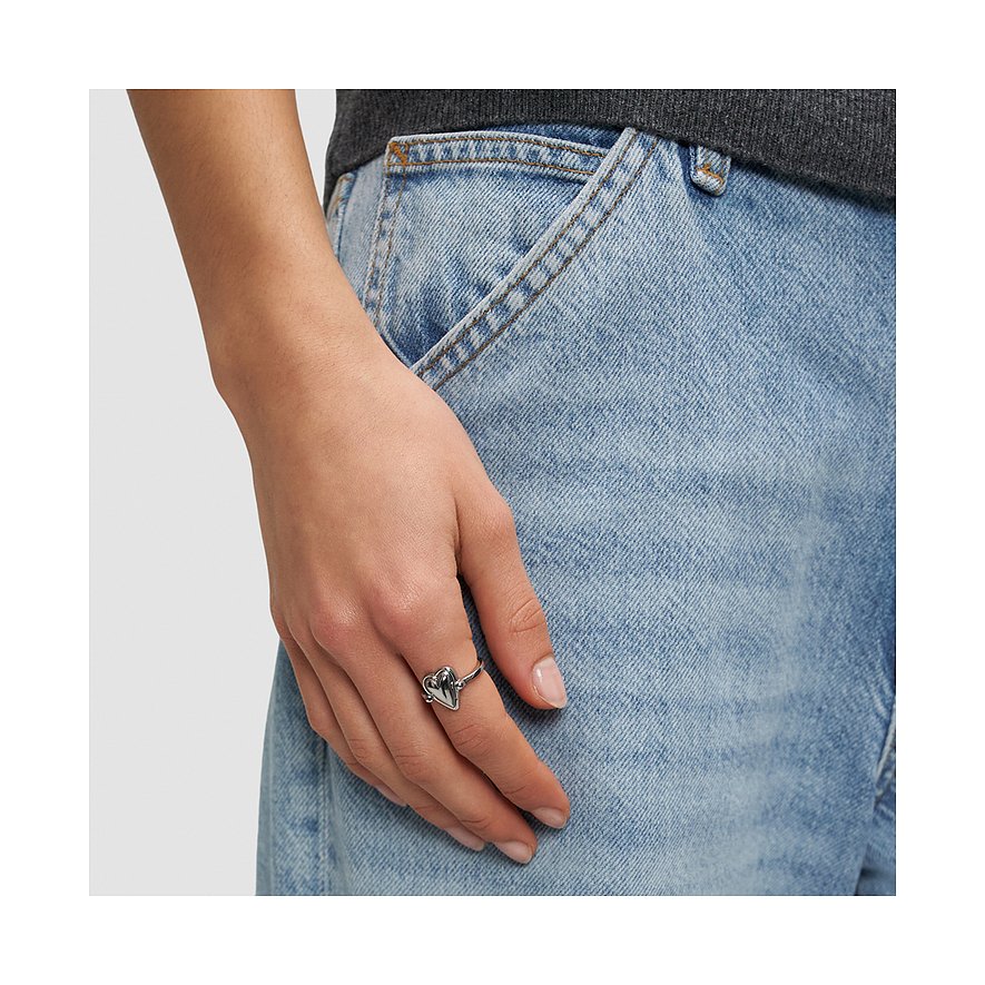 Gros plan d'une main portant une bague Liebeskind en acier inoxydable avec pendentif cœur à l'annulaire.
