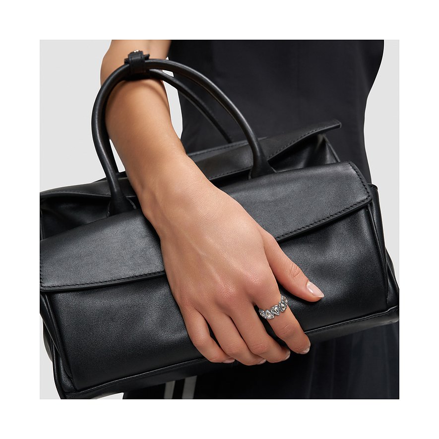 Une bague cœur en acier inoxydable Liebeskind sur une main tenant un sac à main noir.