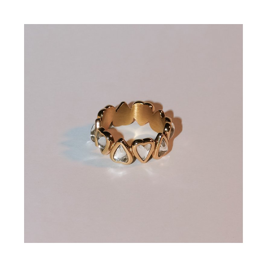 Der Liebeskind Ring aus goldfarbenem Edelstahl ist mit klaren, herzförmigen Schmucksteinen besetzt.