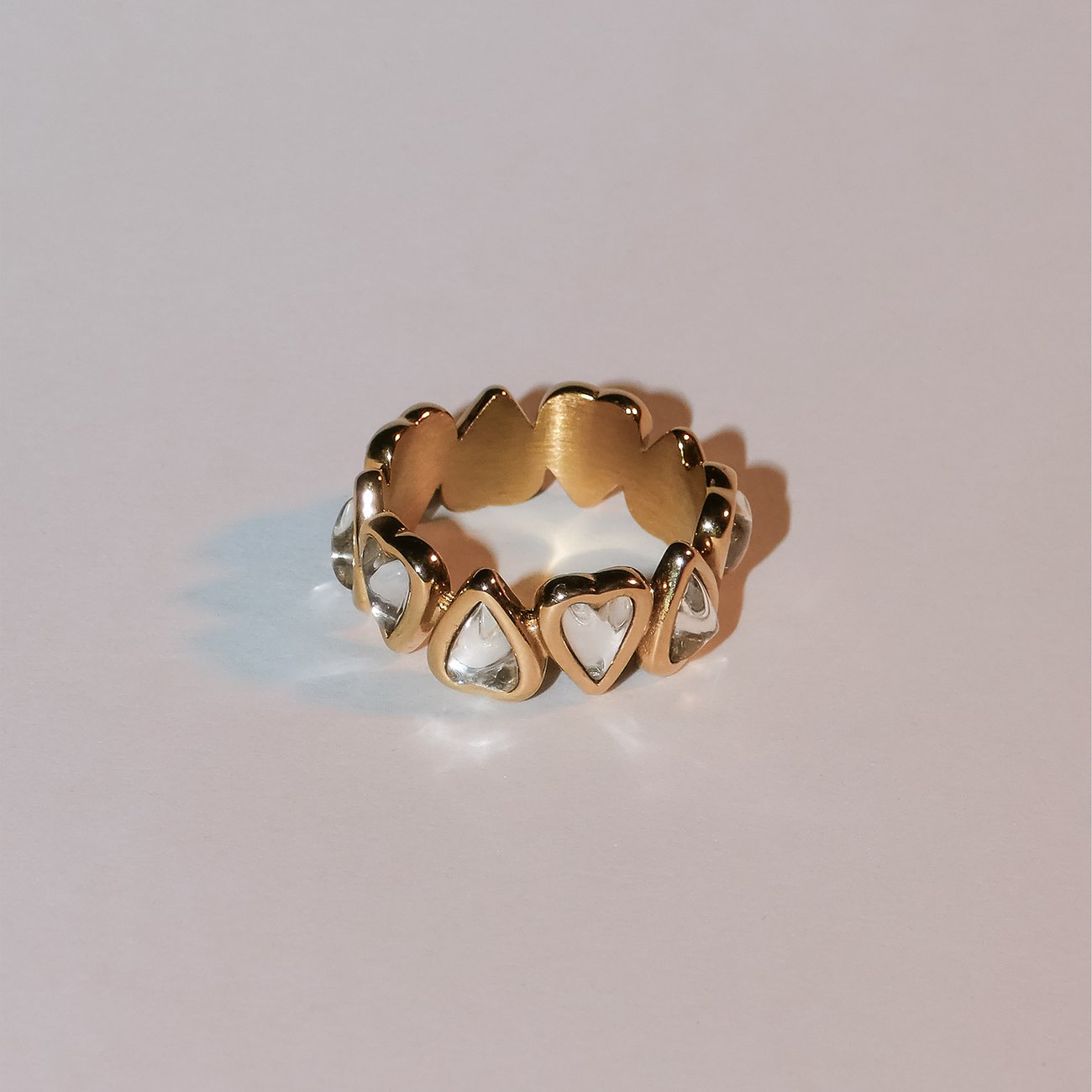 Der Liebeskind Ring aus goldfarbenem Edelstahl ist mit klaren, herzförmigen Schmucksteinen besetzt.