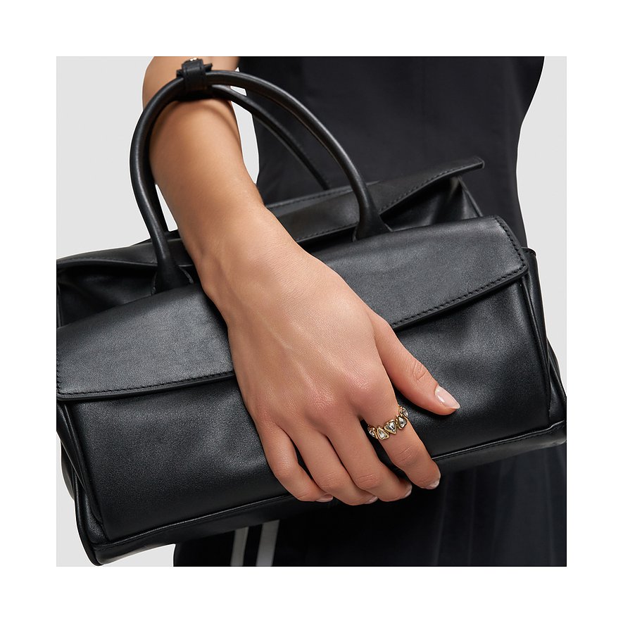 Nahaufnahme einer Hand, die eine schwarze Handtasche hält und einen Liebeskind Ring aus goldfarbenem Edelstahl trägt.