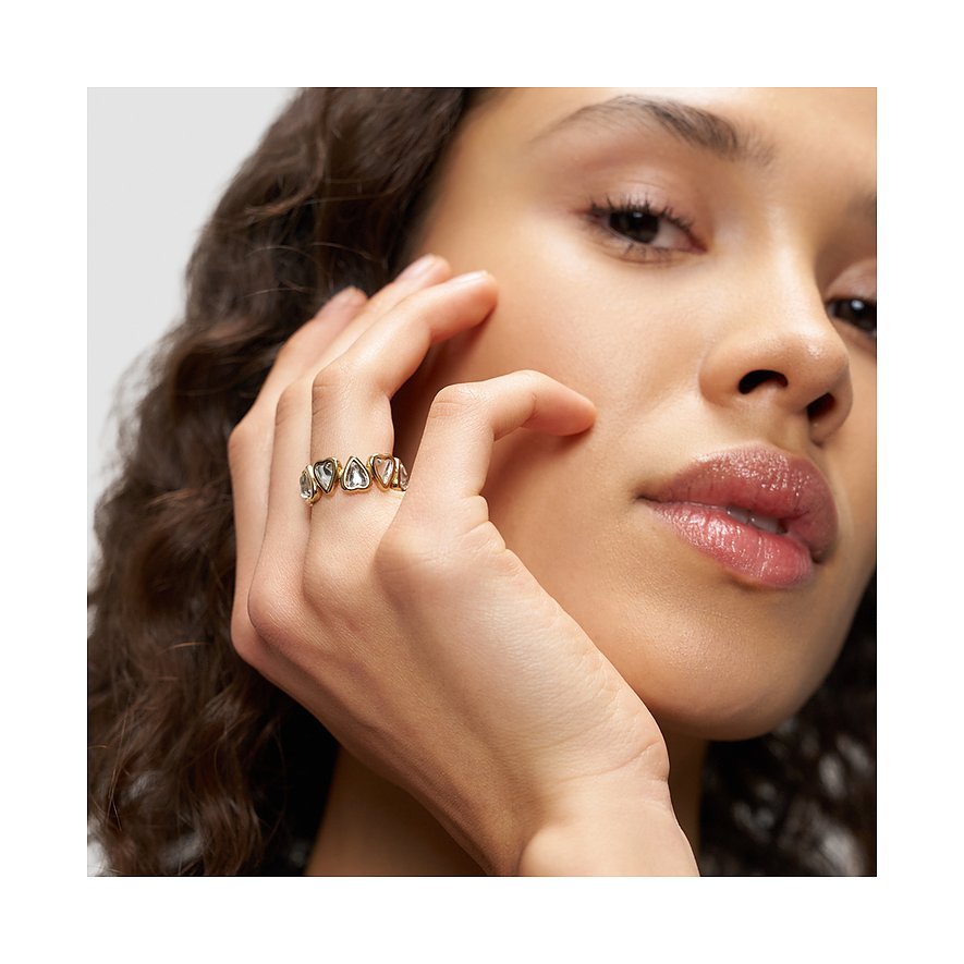 Nahaufnahme eines Liebeskind Rings aus goldfarbenem Edelstahl mit mehreren herzförmigen klaren Schmucksteinen an einer Hand.