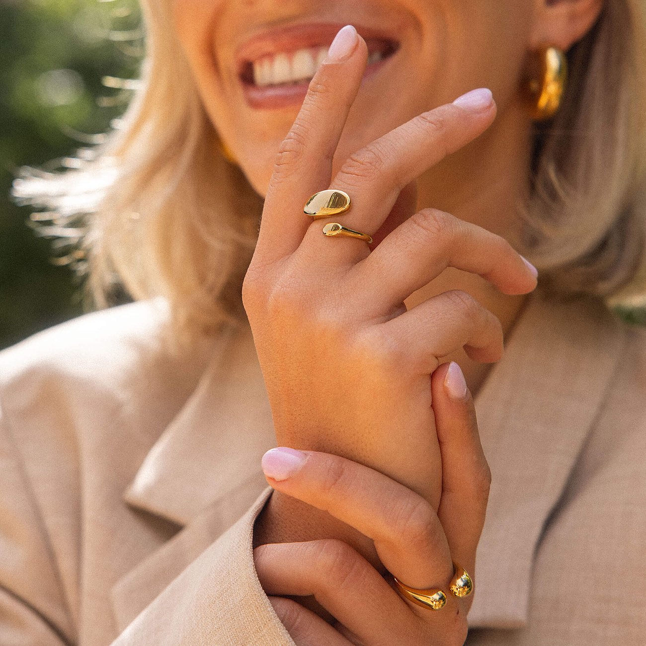 Close-up van een persoon die een Purelei ring van goudkleurig roestvrij staal in het gouden licht houdt.