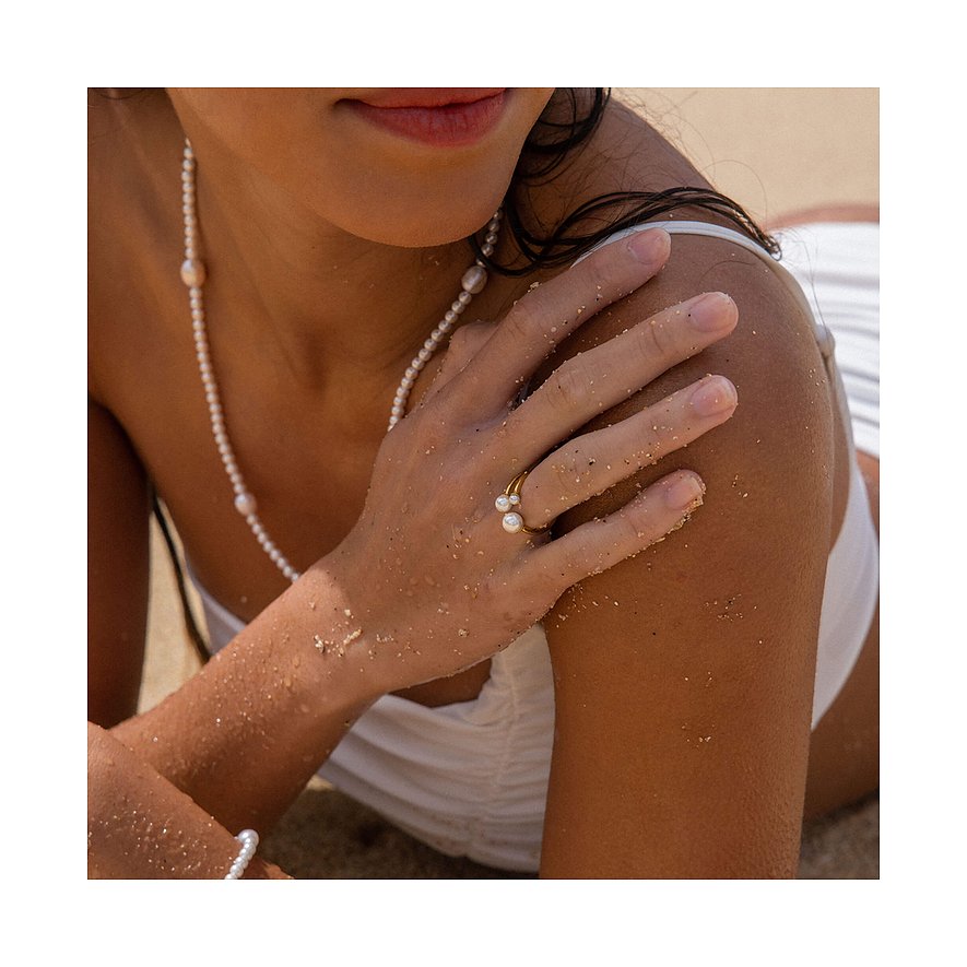 Close-up van Purelei roestvrijstalen ring met twee parels, gedragen aan rechterhand met zandkorrels.
