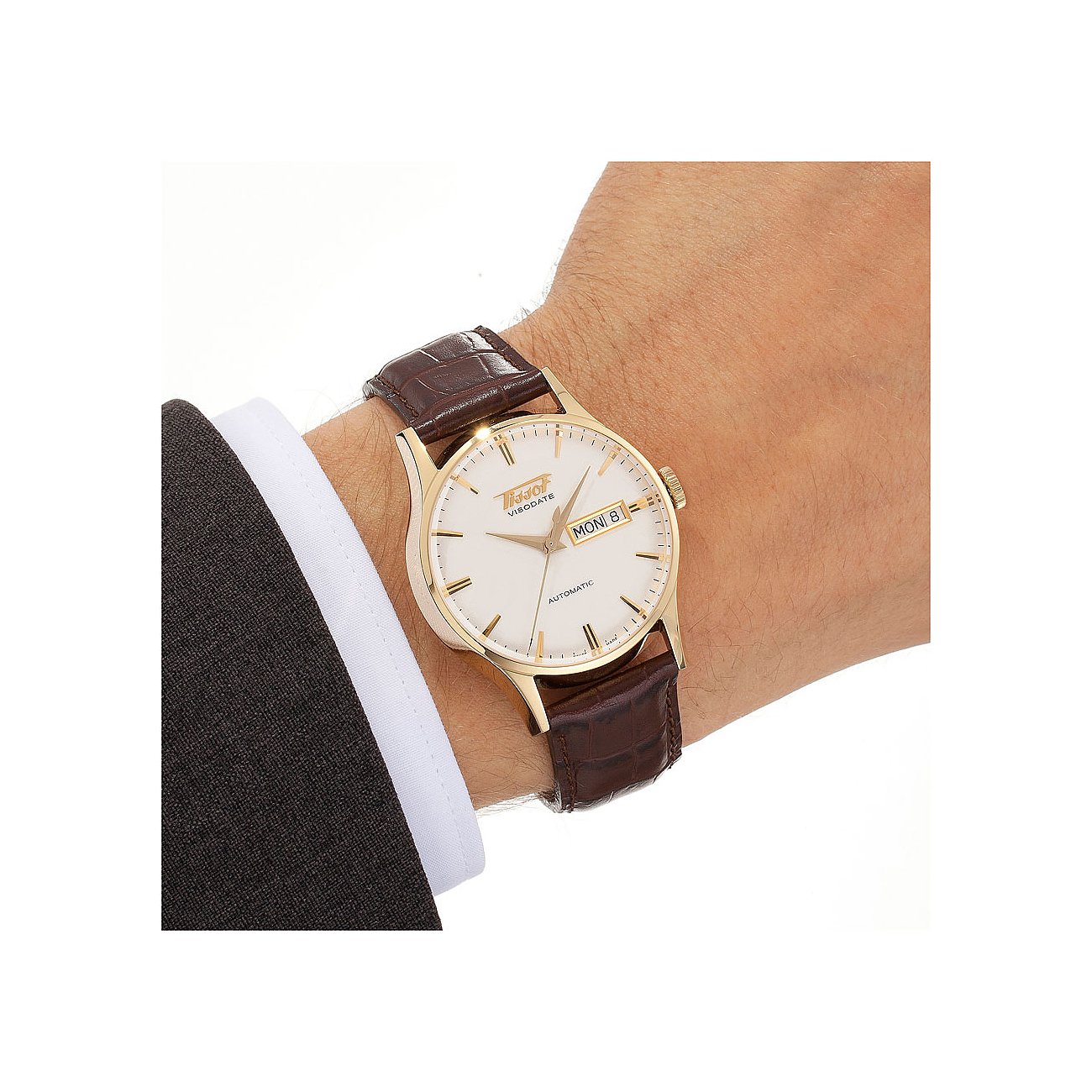 Am Handgelenk getragene Tissot Herrenuhr aus goldfarbenem Edelstahl mit weißem Zifferblatt und braunem Lederarmband.