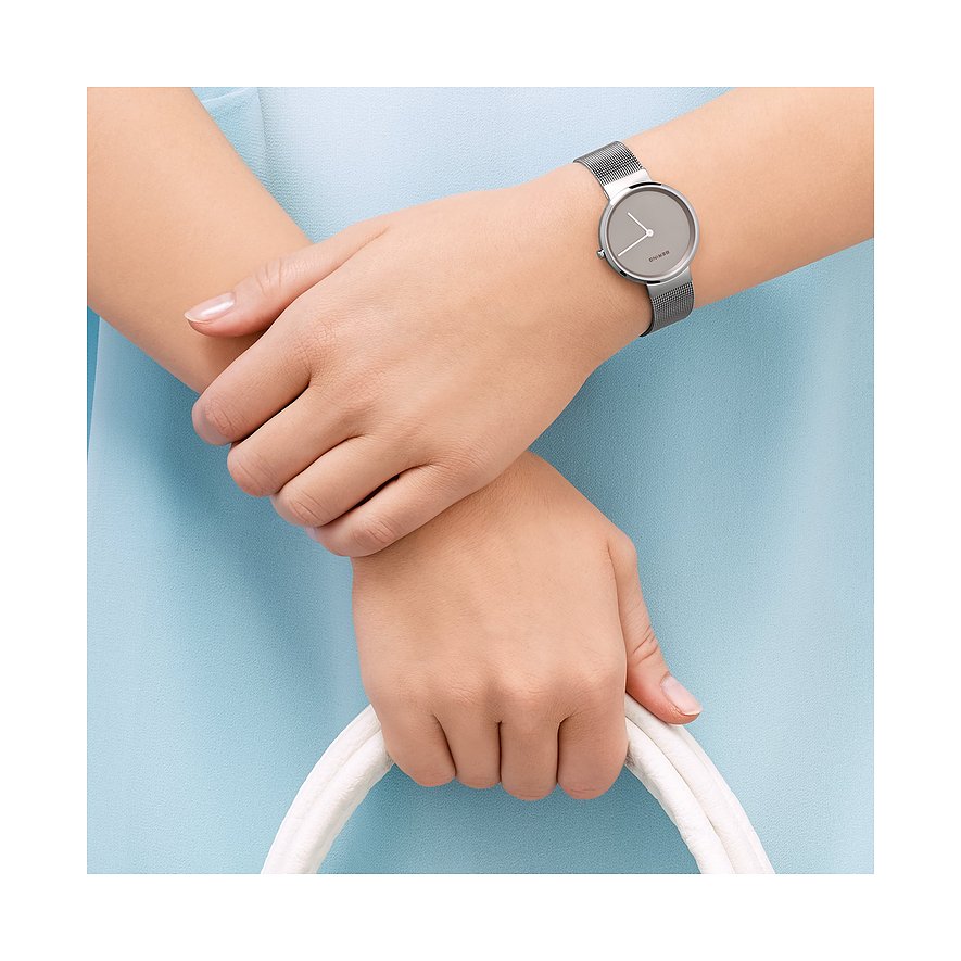 Am Handgelenk einer Frau befindet sich eine Bering Damenuhr aus Edelstahl mit einem Milanaise-Armband und grauem Zifferblatt.