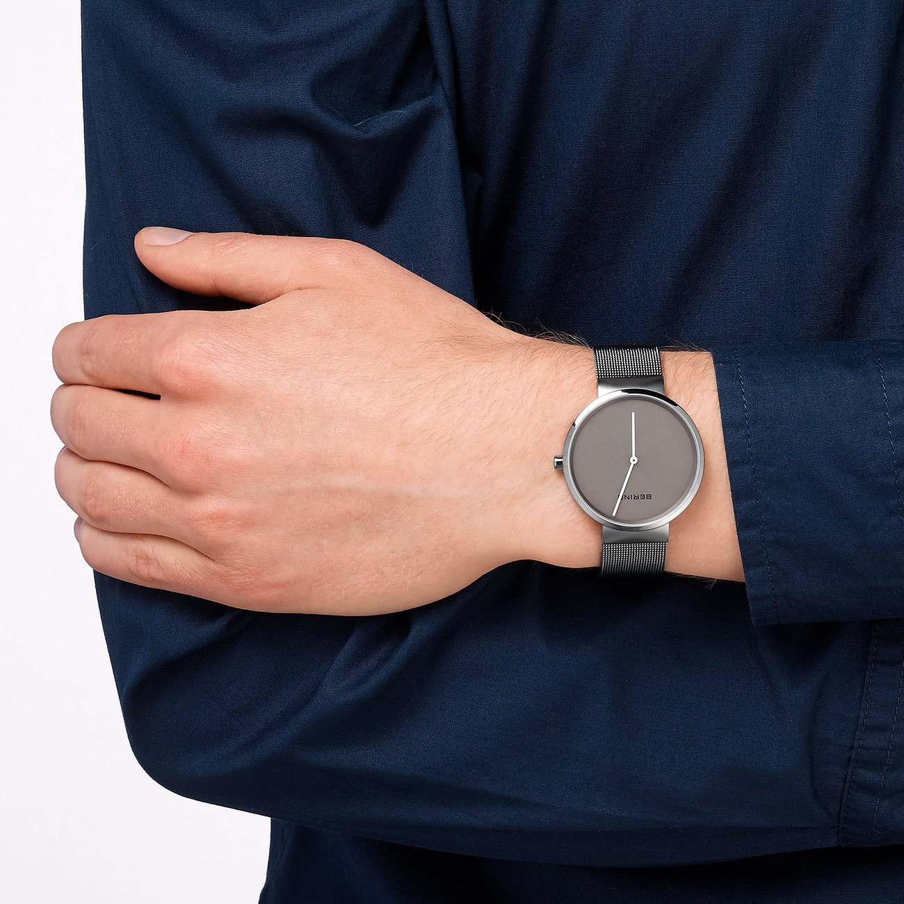 Am Handgelenk eines Mannes getragene Armbanduhr von Bering aus silberfarbenem Edelstahl mit grauem Zifferblatt.