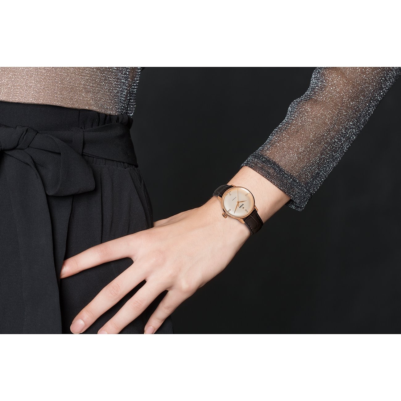 Nahaufnahme einer Rado Damenuhr aus Edelstahl mit braunem Lederarmband am Handgelenk eines Models.