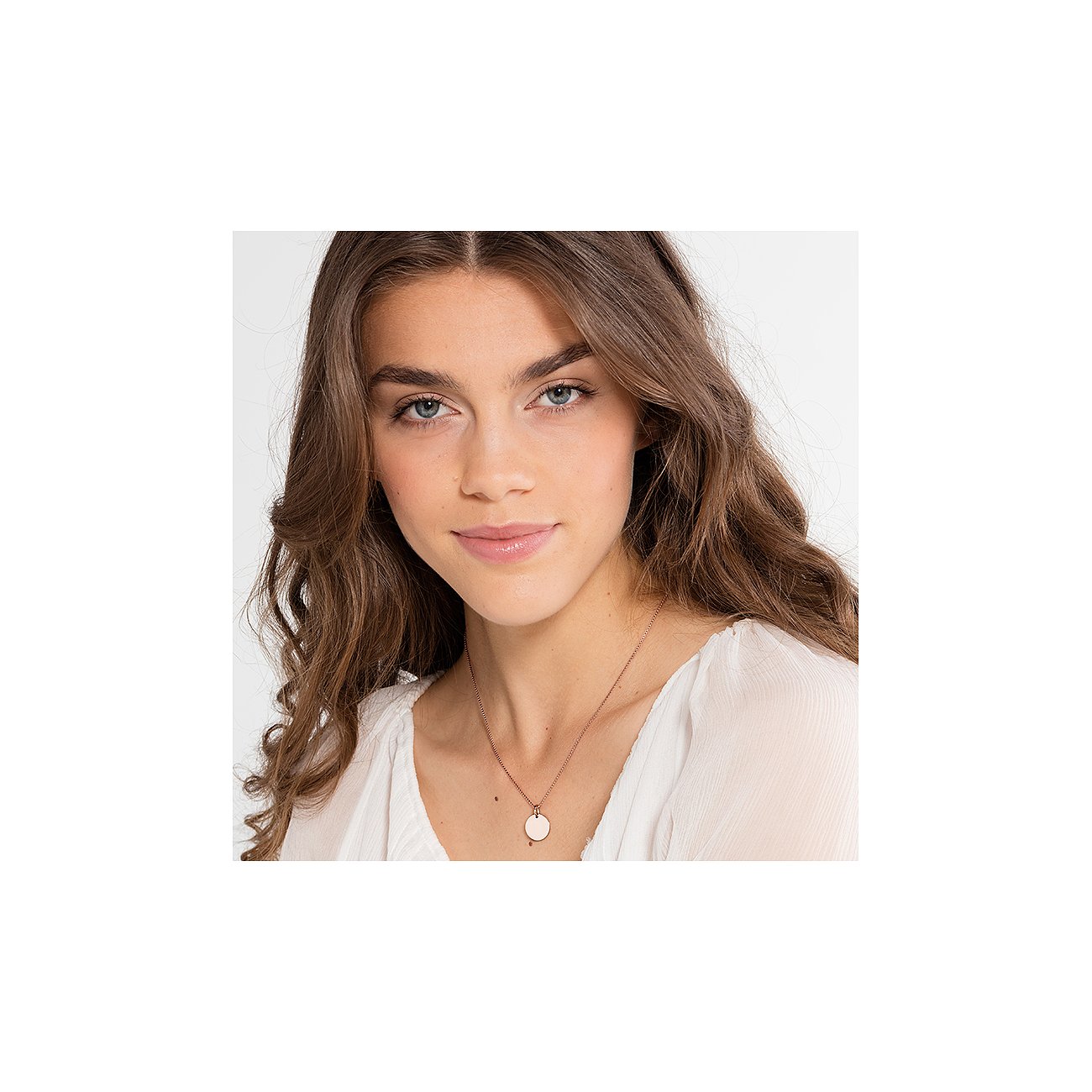 Nahaufnahme einer Frau, die eine roségoldfarbene Thomas Sabo Silberkette mit rundem rosafarbenen Anhänger trägt.
