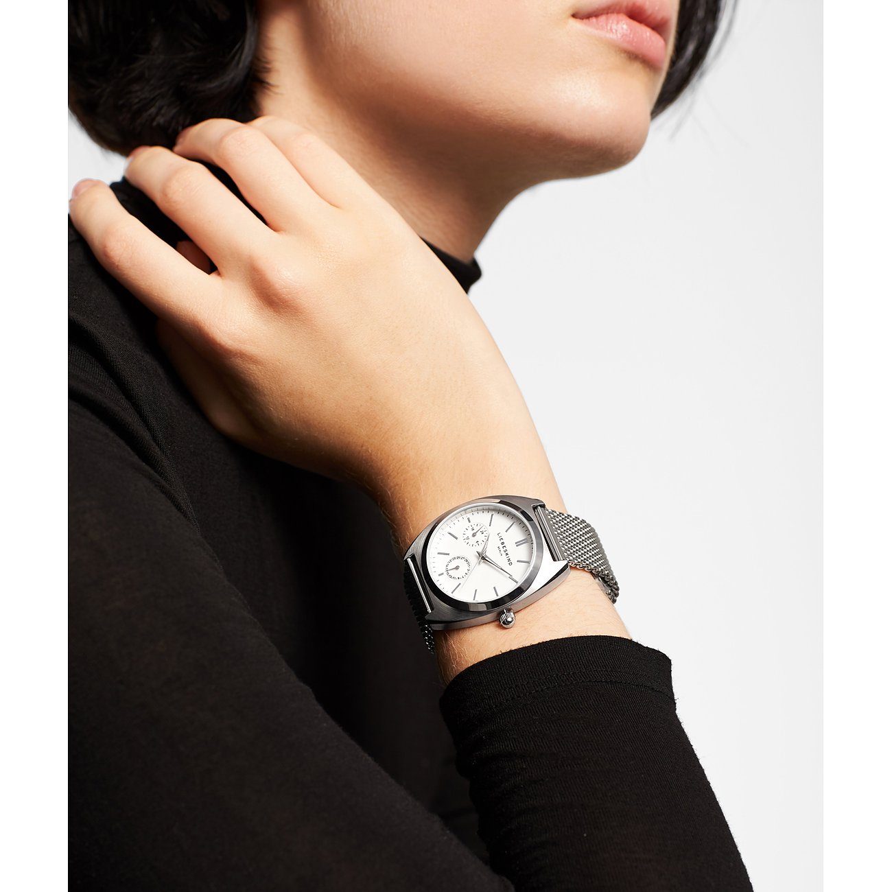 Nahaufnahme einer Liebeskind Damenuhr aus Edelstahl mit silbernem Mesh-Armband und weißem Zifferblatt am Handgelenk.