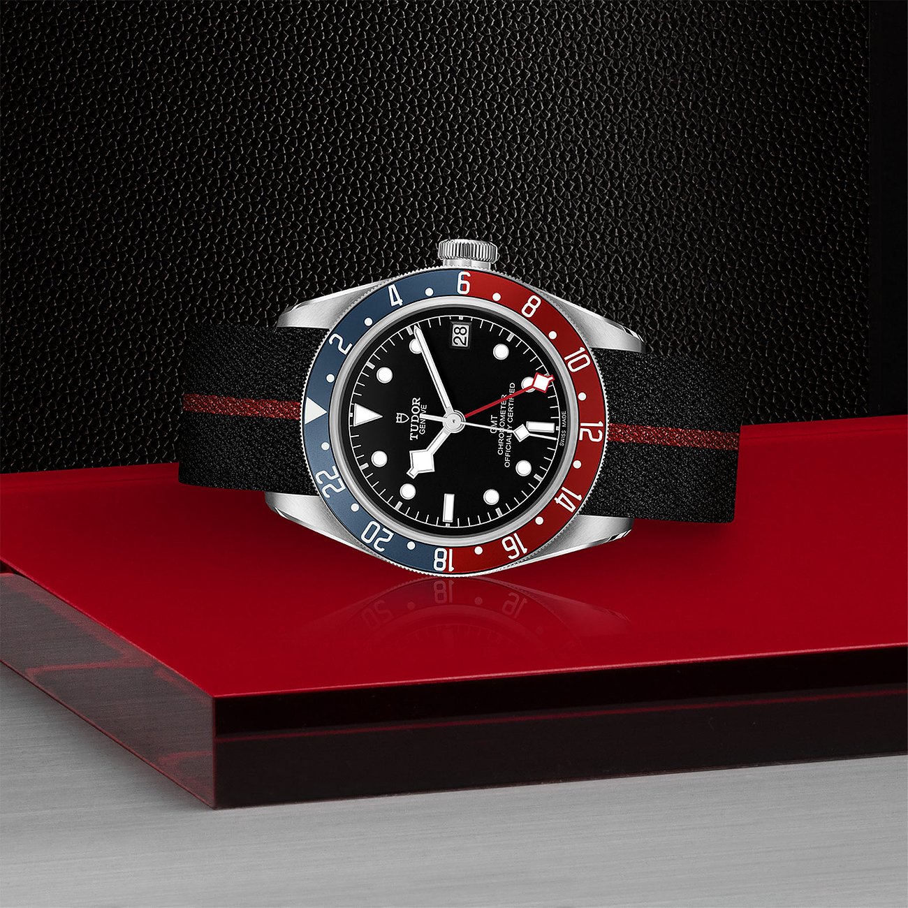 Tudor Herrenuhr mit Edelstahlgehäuse, schwarzem Zifferblatt und rot-blauer Lünette.