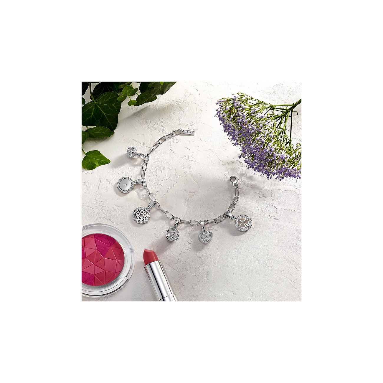 JETTE Karabinerarmband aus rhodiniertem 925er Silber mit mehreren Anhängern, besetzt mit Zirkonia, auf hellem Hintergrund.