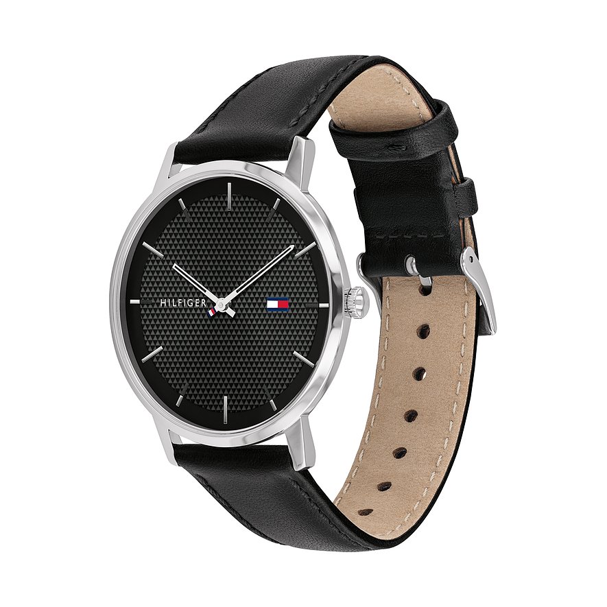 Eine schwarze Tommy Hilfiger Herrenuhr aus Edelstahl mit genarbtem schwarzem Zifferblatt steht auf weißem Hintergrund.