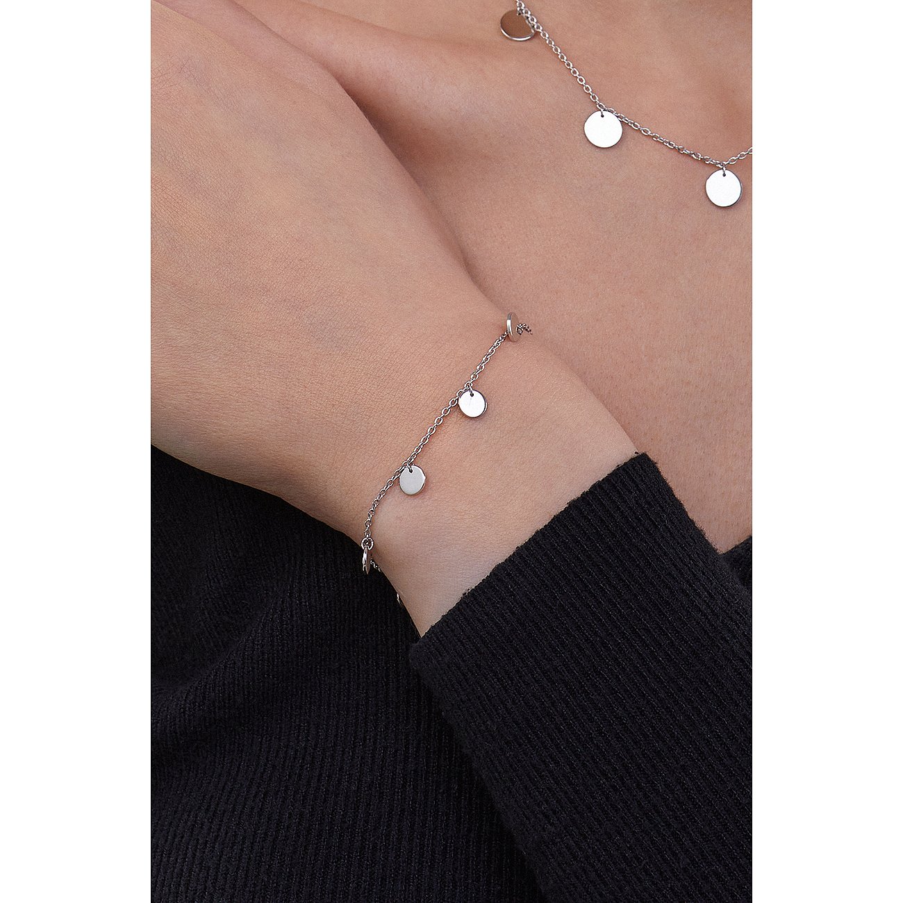Caï Armband aus 925er Silber mit dünner Kette und kleinen, runden Anhängern am Handgelenk getragen.