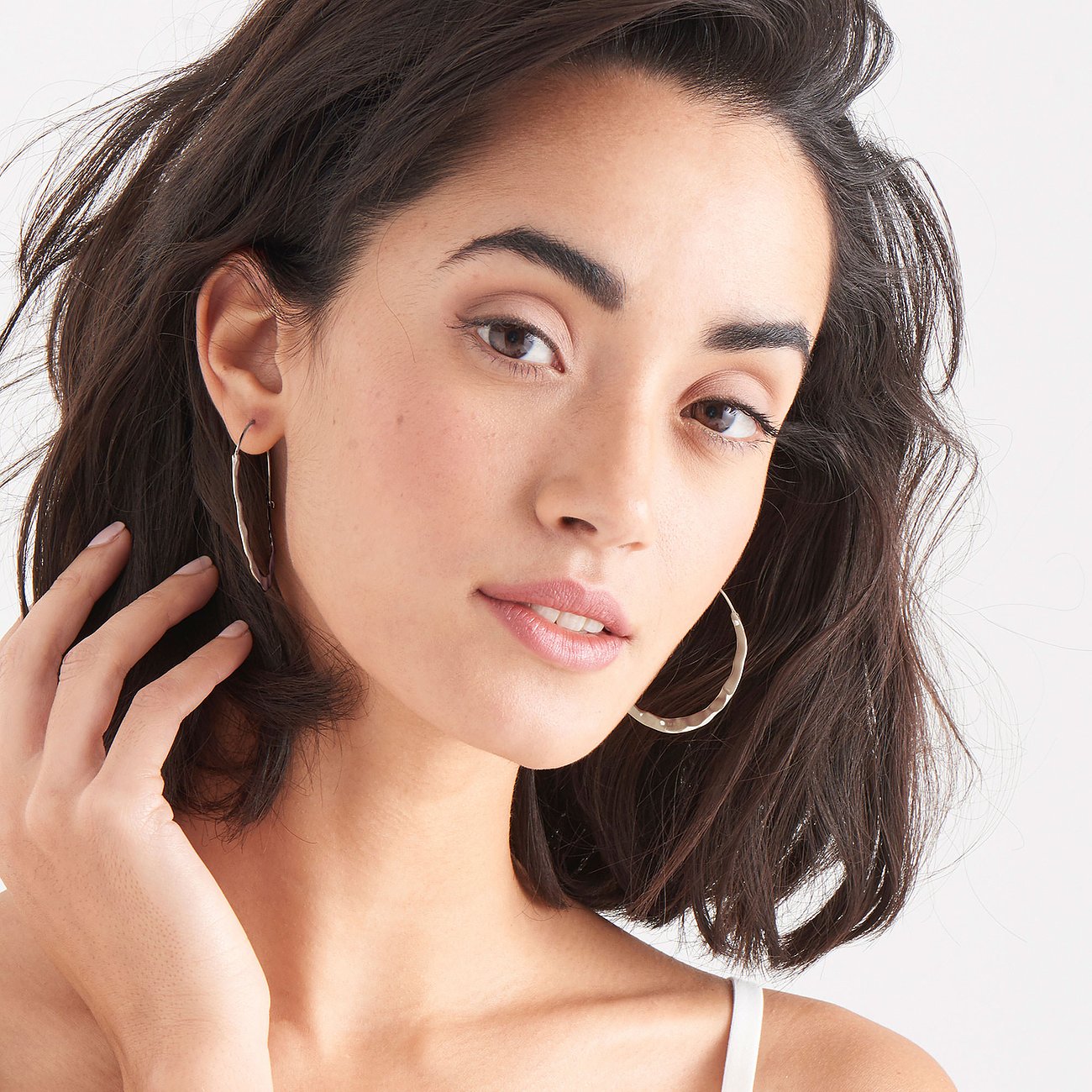 Model trägt Ania Haie Ohrschmuck aus 925er Silber: gehämmerten, runden Creolen rechts, lange, schmale Creole links.