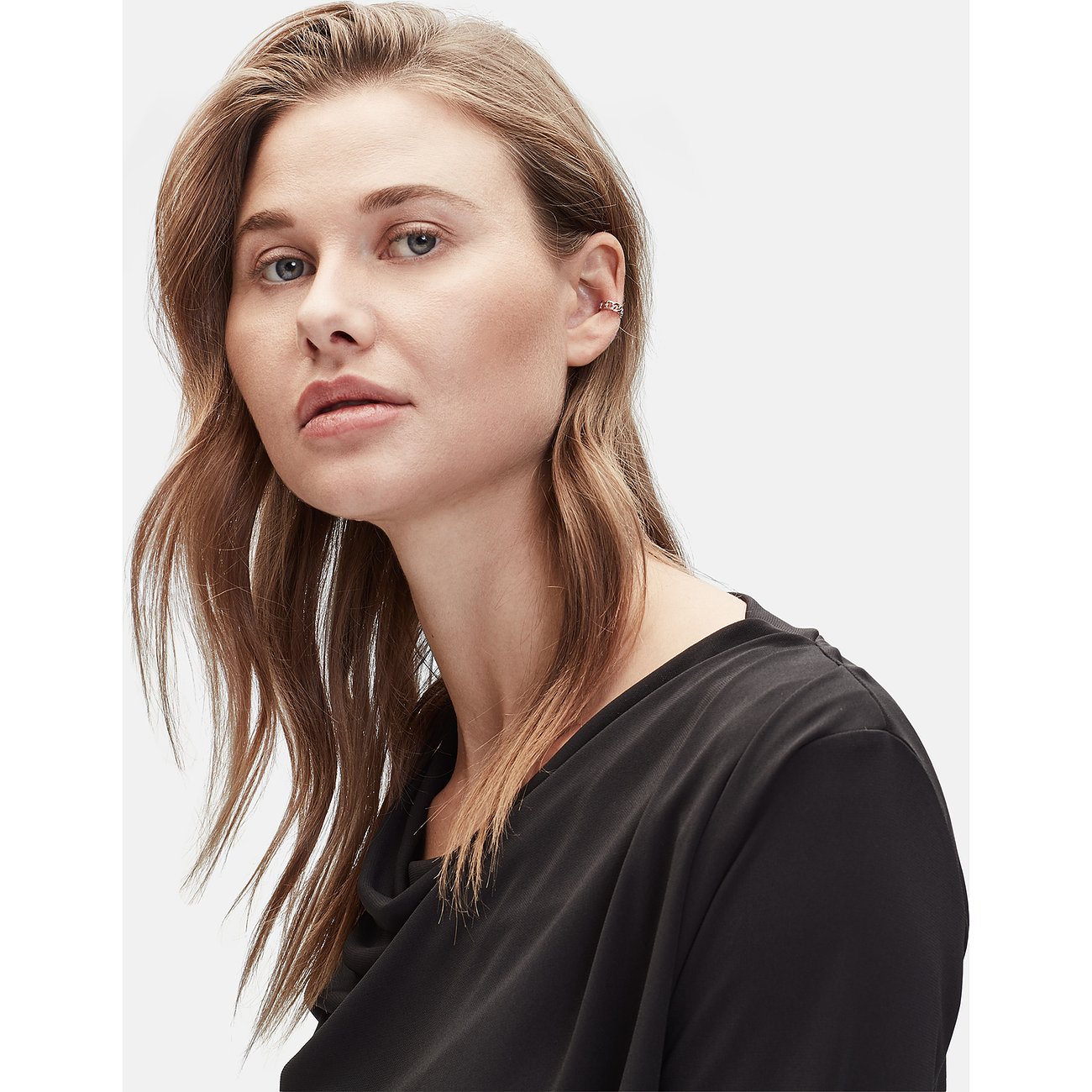 Eine Frau, die einen Liebeskind Edelstahl-Ohrschmuck in Form eines silberfarbenen Ear Cuffs trägt.