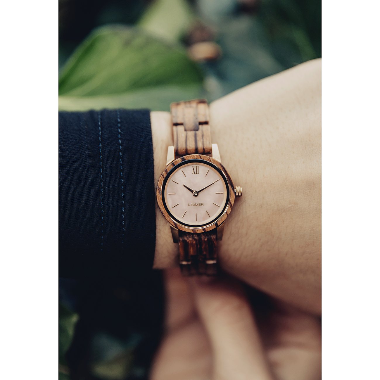 Närbild av en Laimer damklocka i trä med ljus urtavla på en handled.
