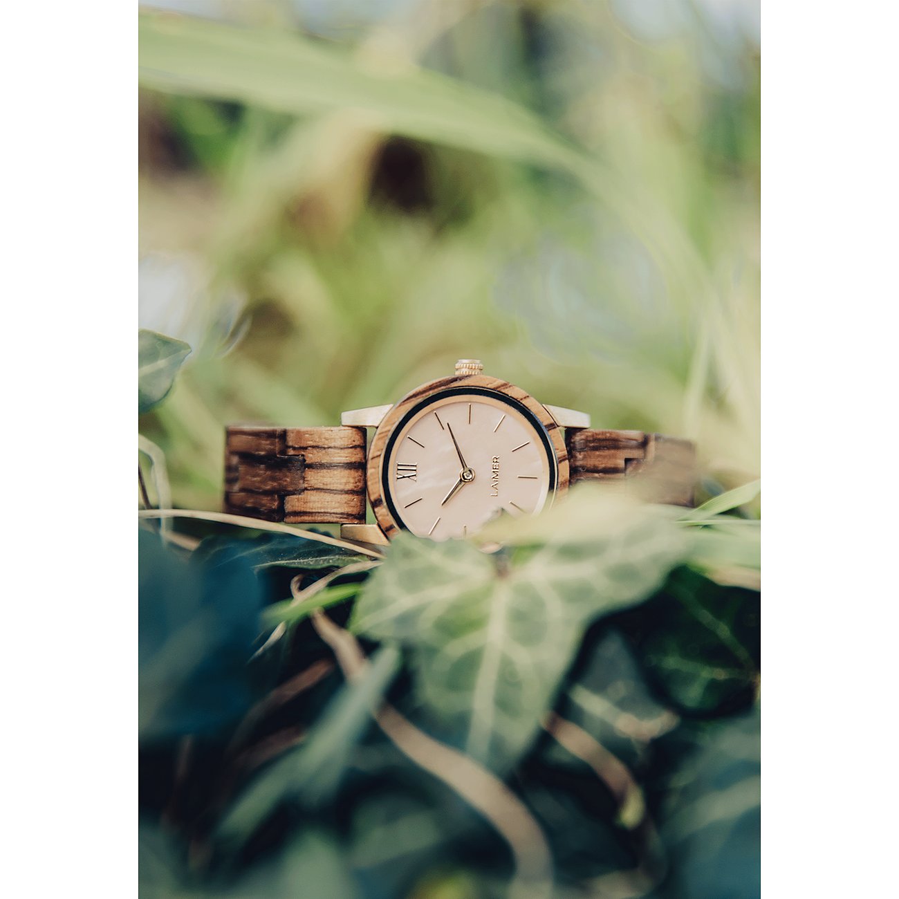 Närbild av en rund Laimer damklocka i ljust trä med silverfärgat boett och ljusbeige urtavla.