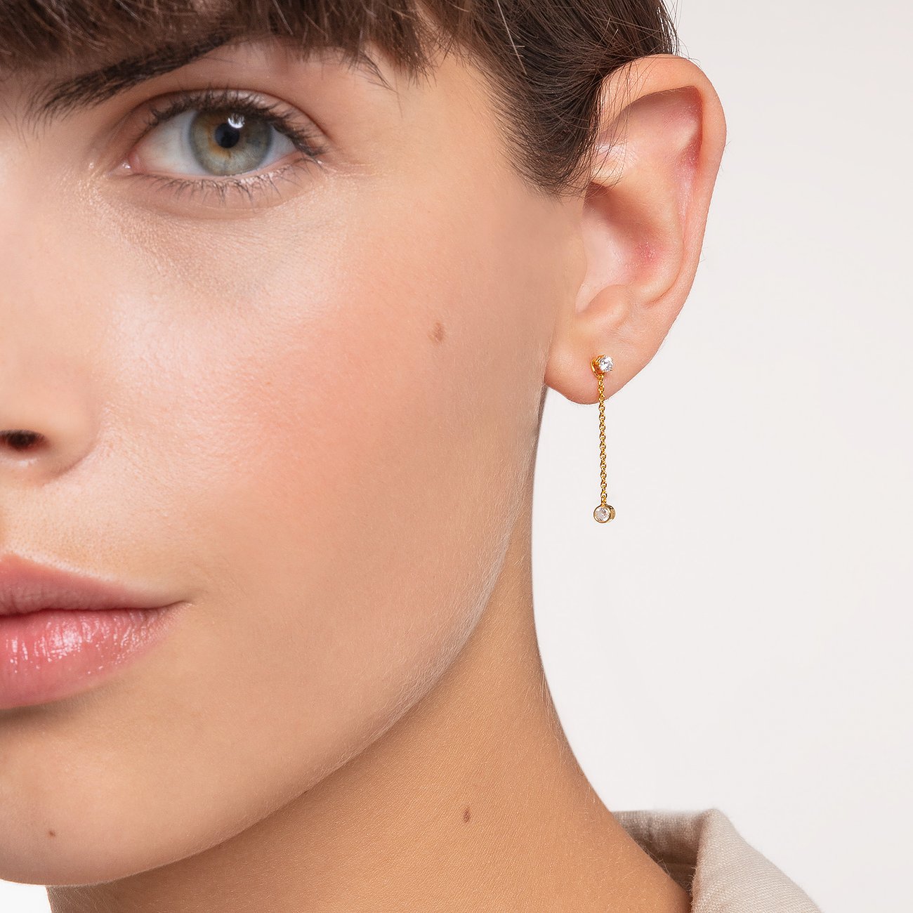 Nahaufnahme einer Frau, die einen goldenen Thomas Sabo Ohrstecker aus Silber 925 mit Zirkonia trägt.