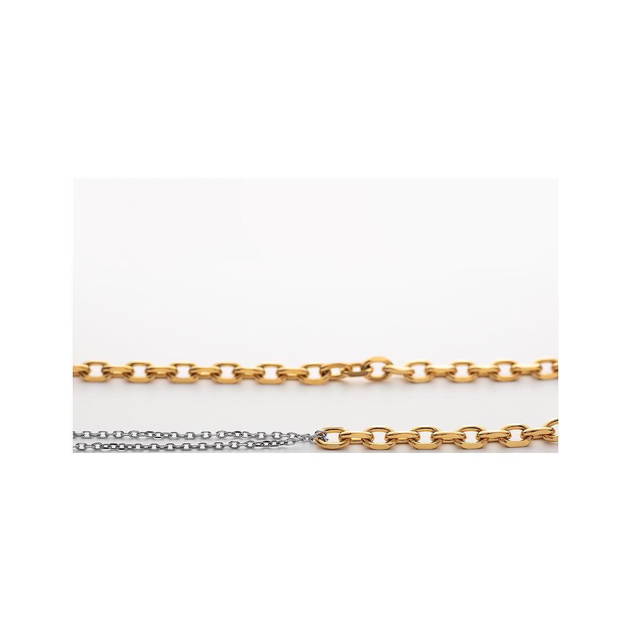 Zwei Paul Hewitt Halsketten aus glänzendem Edelstahl in Gold und Silber liegen parallel auf weißem Grund.