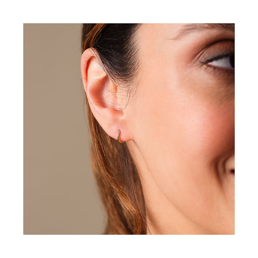 FAVS Ohrschmuck: Ein kleines, glänzendes Gelbgold Ohrring am Ohrläppchen einer Frau, von der Seite.