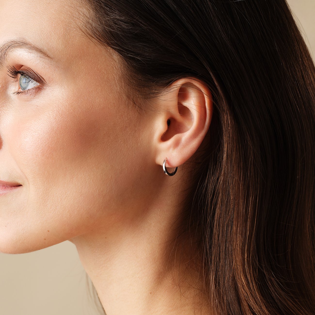FAVS 925er Silber Creolen am Ohr eines Models. Das Ohr schmückt ein einzelner runder Ohrring aus Silber.
