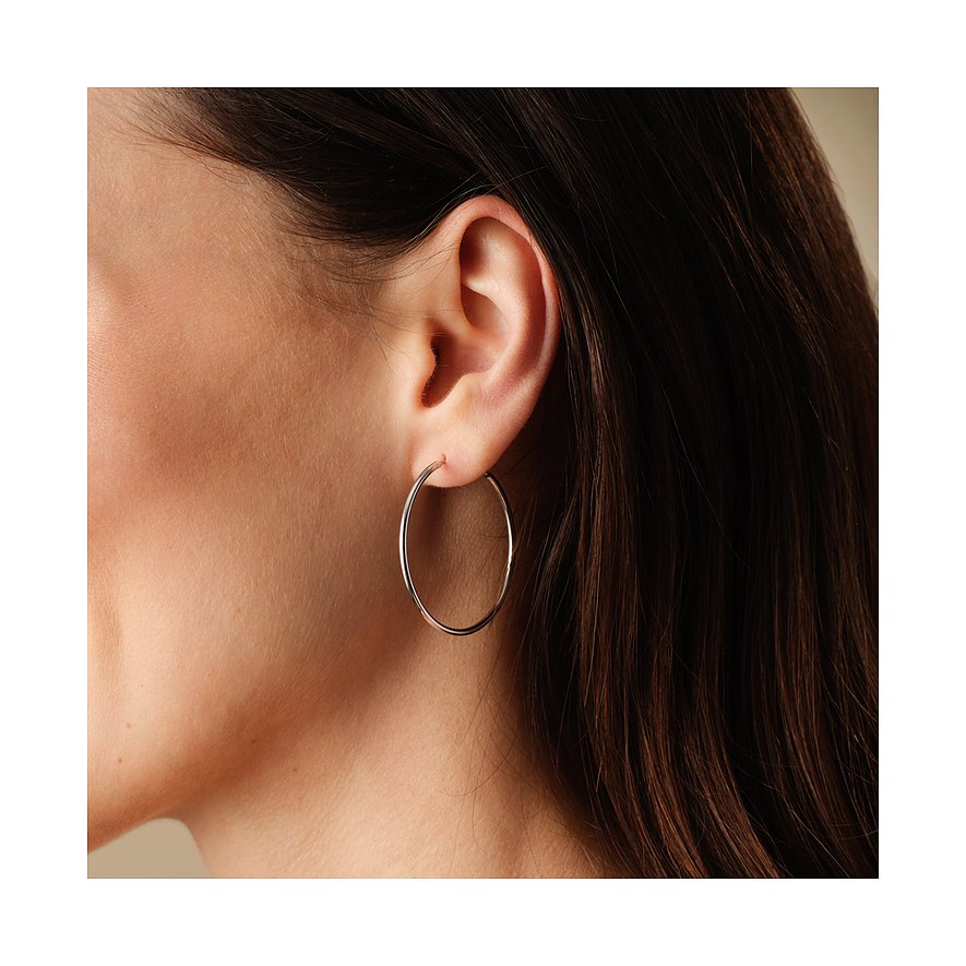 FAVS örhängen: Silvercreoler i 925 silver, bärs av en kvinna och visas från sidan.