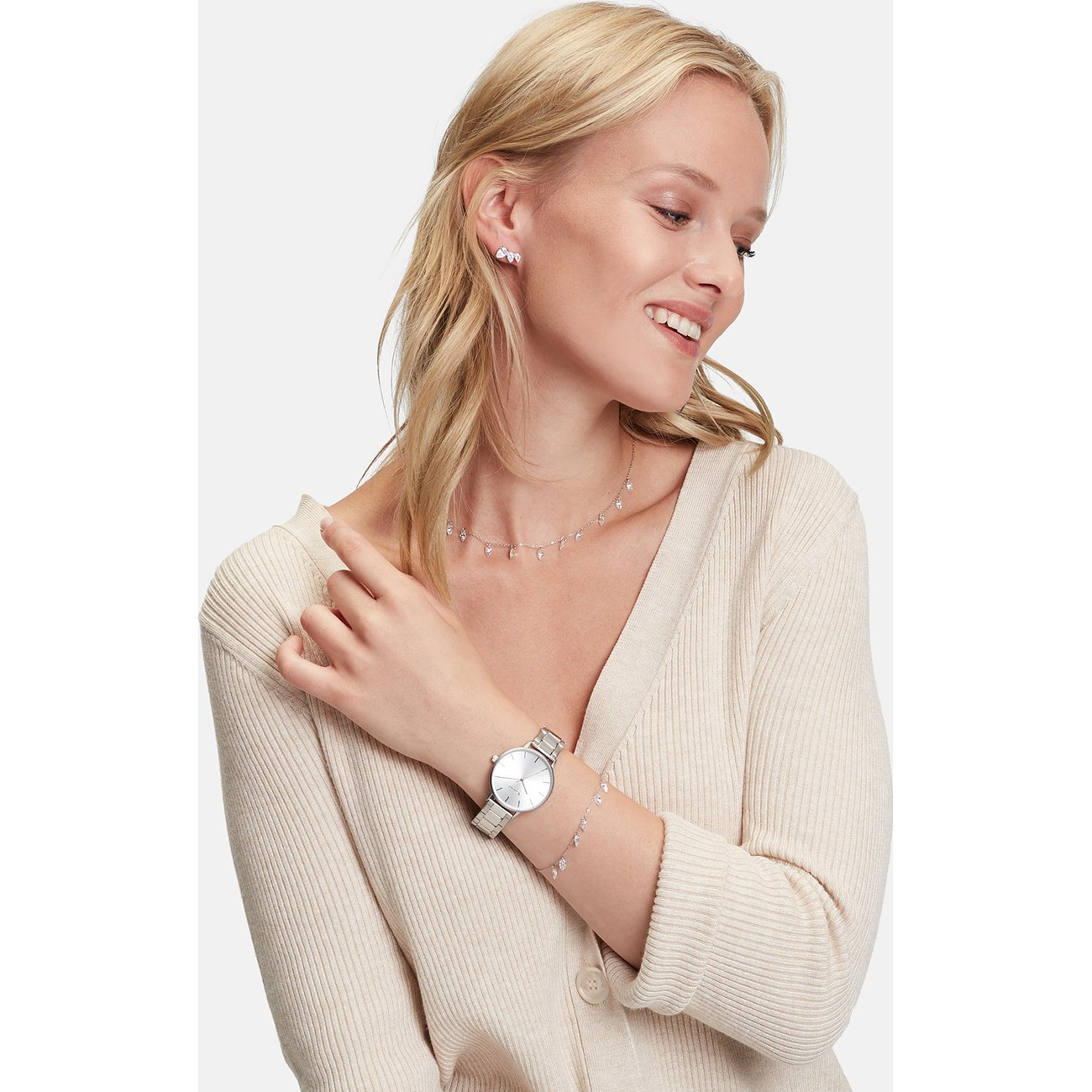 Eine lächelnde Frau trägt eine Tamaris Halskette mit Zirkonia-Farbsteinen aus Edelstahl und passende Ohrringe und Armband.