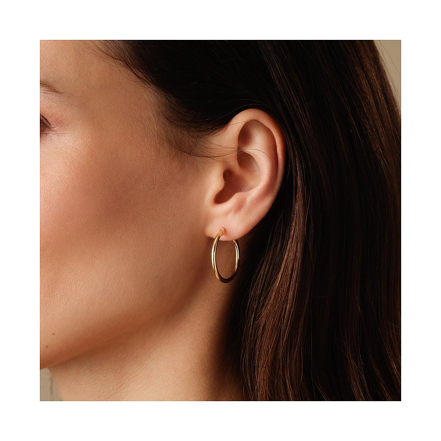 FAVS ørestykker: Nærbillede af en kvinde med en enkelt rund creolørering i guld.