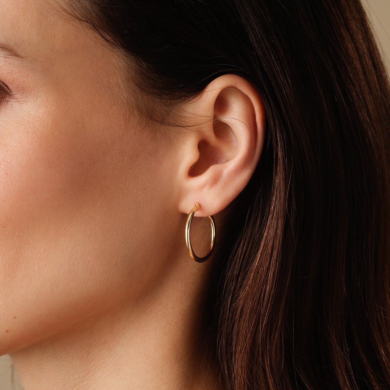 FAVS ørestykker: Nærbillede af en kvinde med en enkelt rund creolørering i guld.