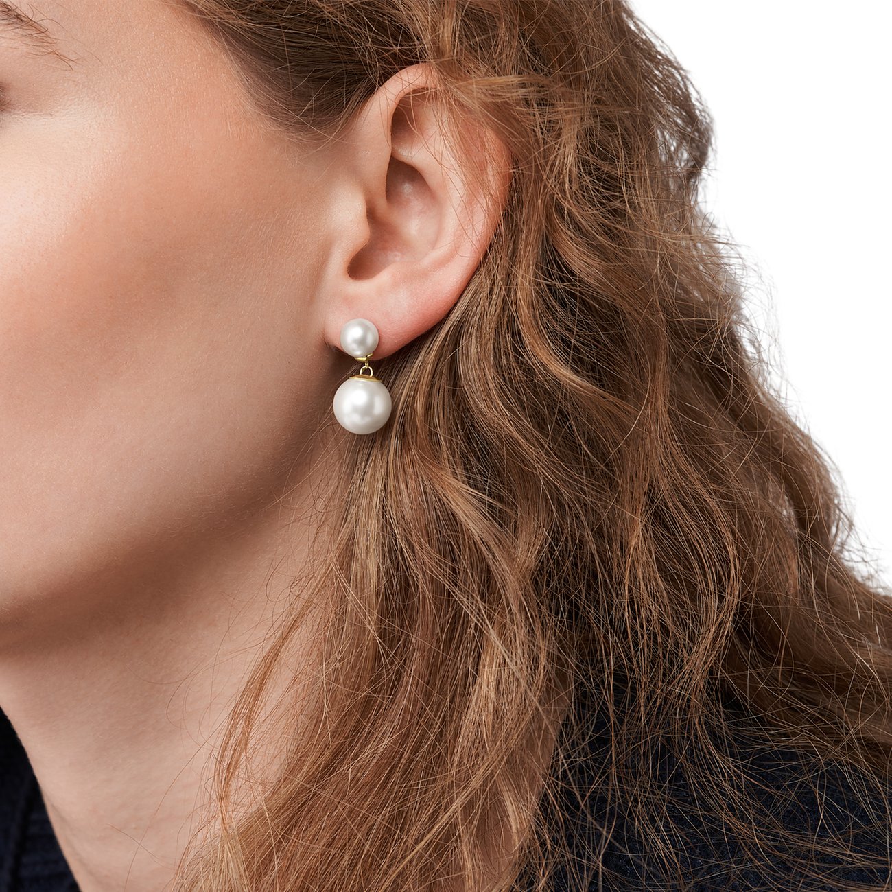 Skagen örhänge i rostfritt stål med två hängande pärlor buret på ett öra, närbild.