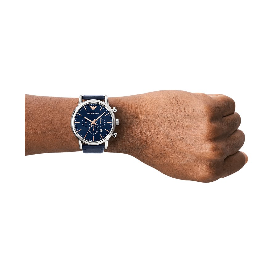 Eine dunkelhäutige Hand trägt eine Emporio Armani Herrenuhr aus blauem Leder und Edelstahl mit blauem Zifferblatt.