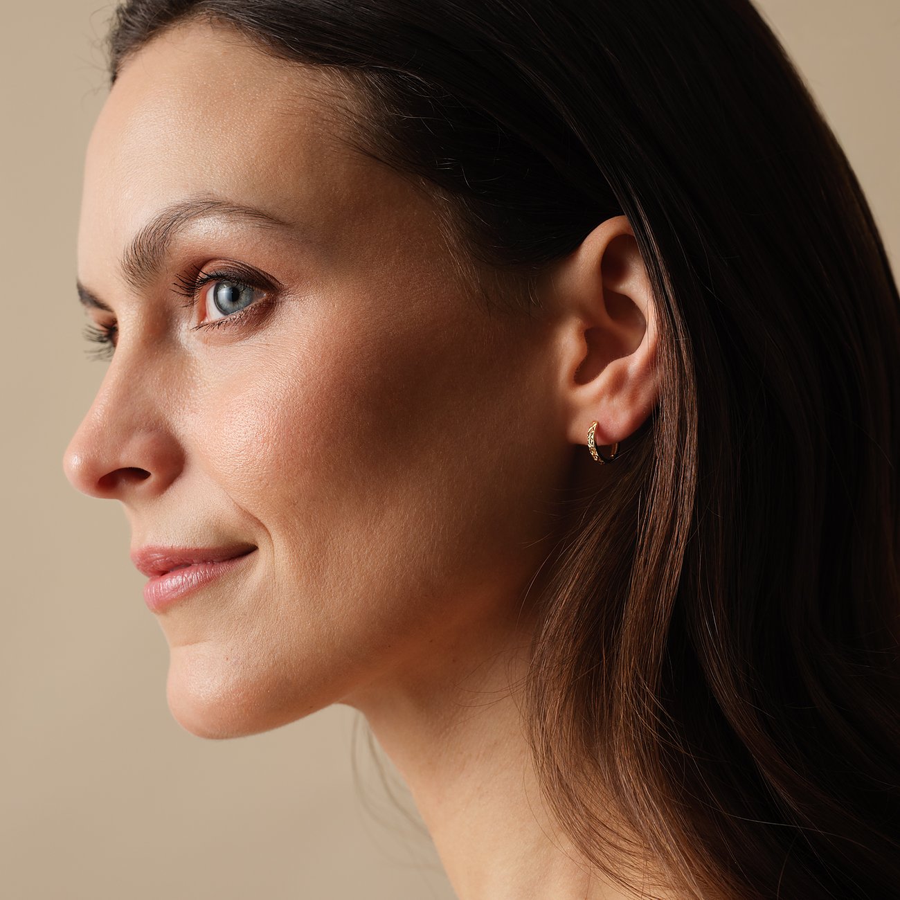 FAVS 375 örhänge i gult guld, buret av en kvinna. Örhänget är litet och subtilt.