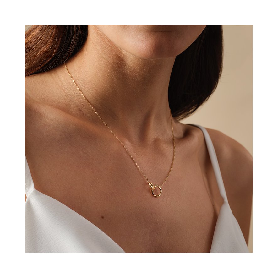 Een vrouw draagt een FAVS 375 geelgouden halsketting met een kleine, ronde oogje als hanger op haar borst.