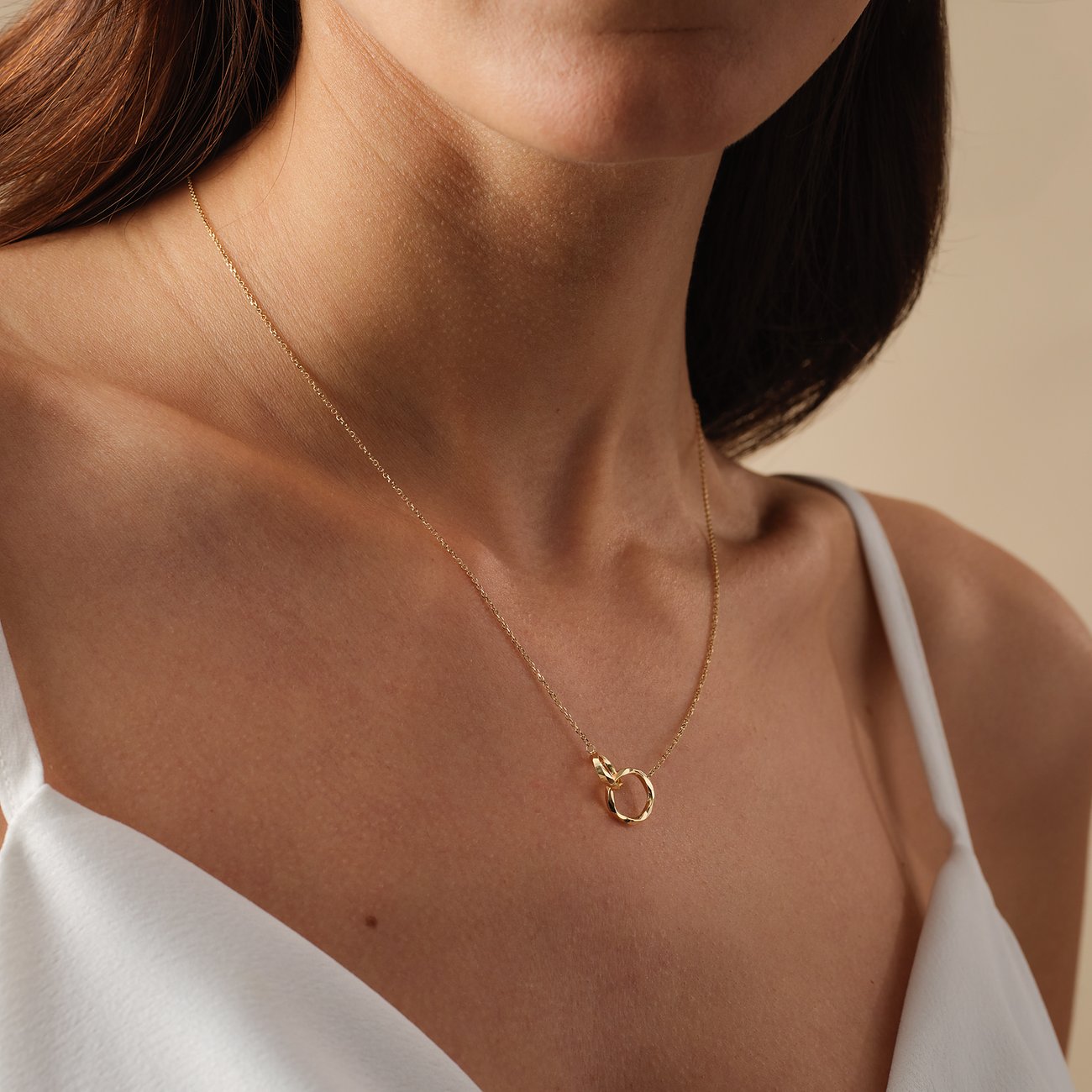 Een vrouw draagt een FAVS 375 geelgouden halsketting met een kleine, ronde oogje als hanger op haar borst.