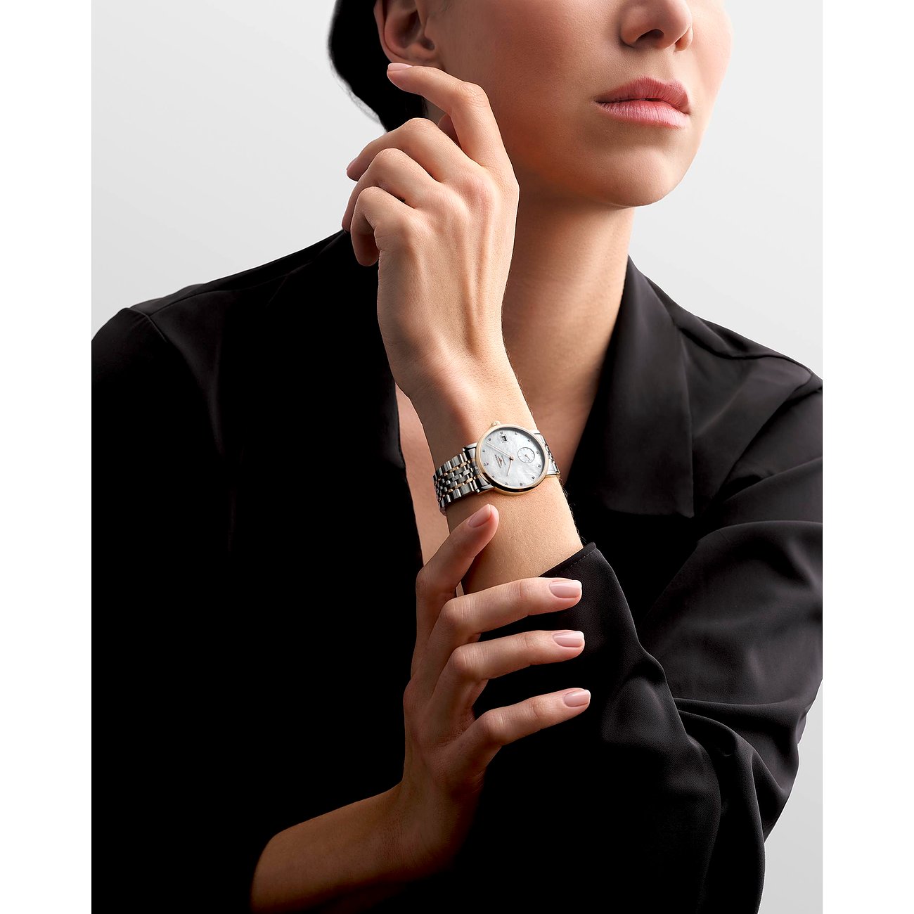 Nahaufnahme einer Longines Damenuhr aus Edelstahl und Roségold mit Diamanten am Handgelenk eines Models.