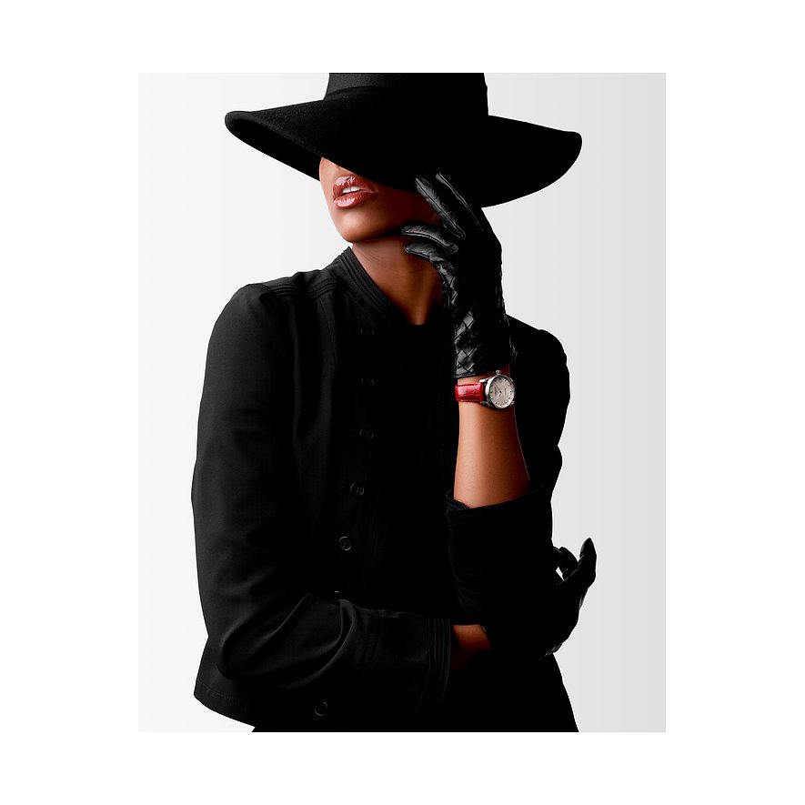 Eine Frau mit schwarzem Hut und Handschuhen trägt eine Longines Damenuhr aus Edelstahl mit Diamanten und roten Armband.