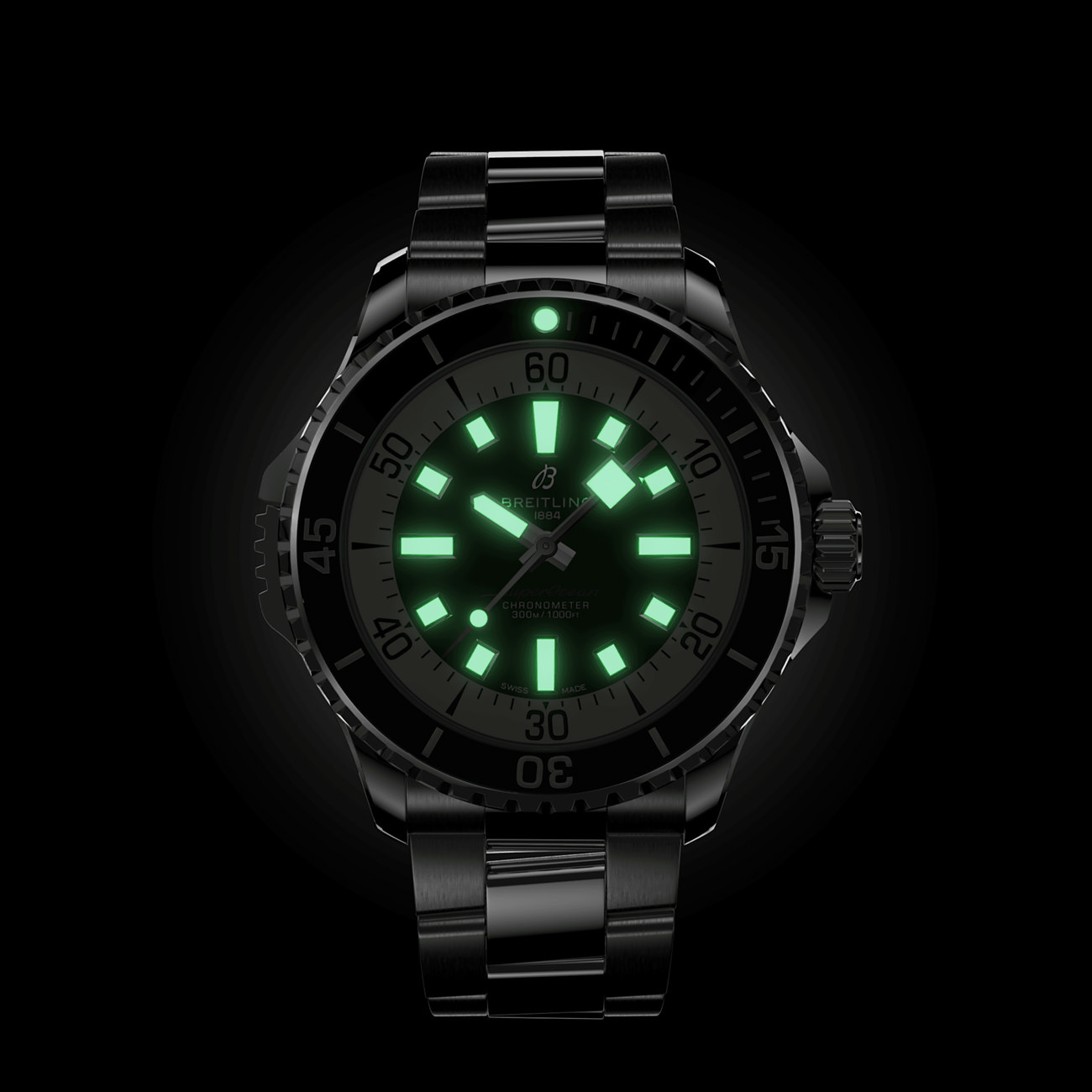 Nahaufnahme einer Breitling Herrenuhr aus blauem Edelstahl mit leuchtenden Zeigern und Indizes in der Dunkelheit.