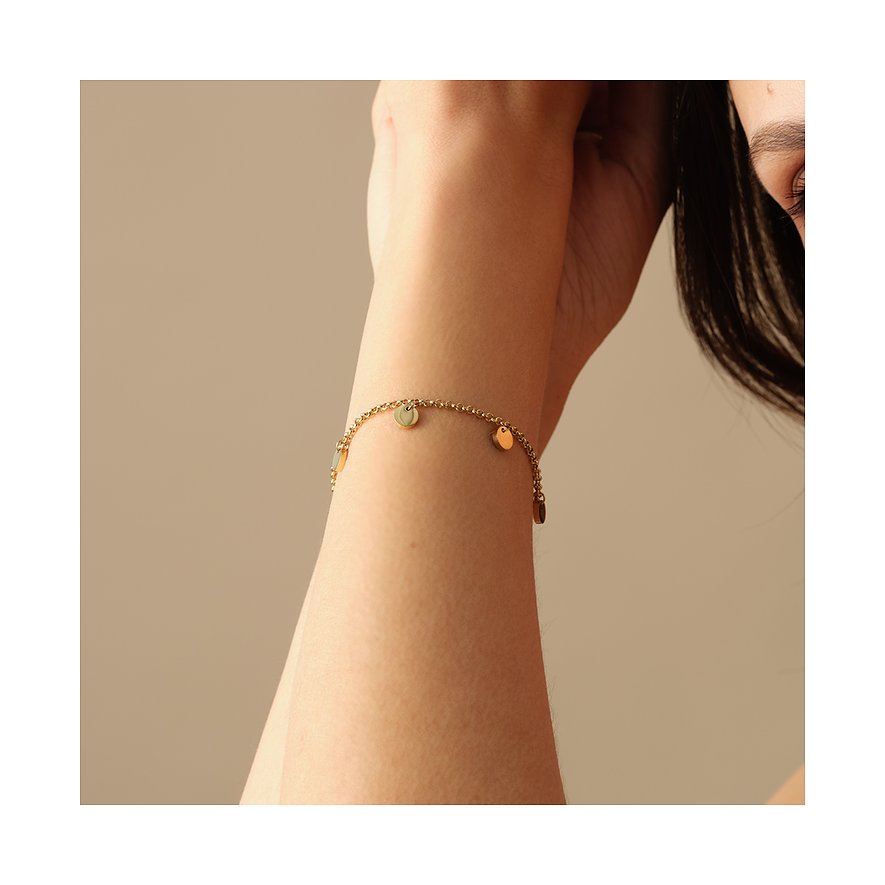 Ein glänzendes, goldenes FAVS Armband aus Edelstahl mit kleinen hängenden runden Scheiben, getragen an einem Arm.