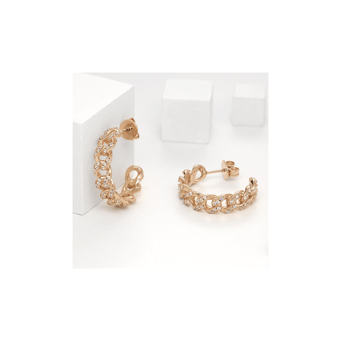 Två JETTE örhängen i roséguldpläterat silver med länkar, prydda med gnistrande färgade zirkoniastenar.