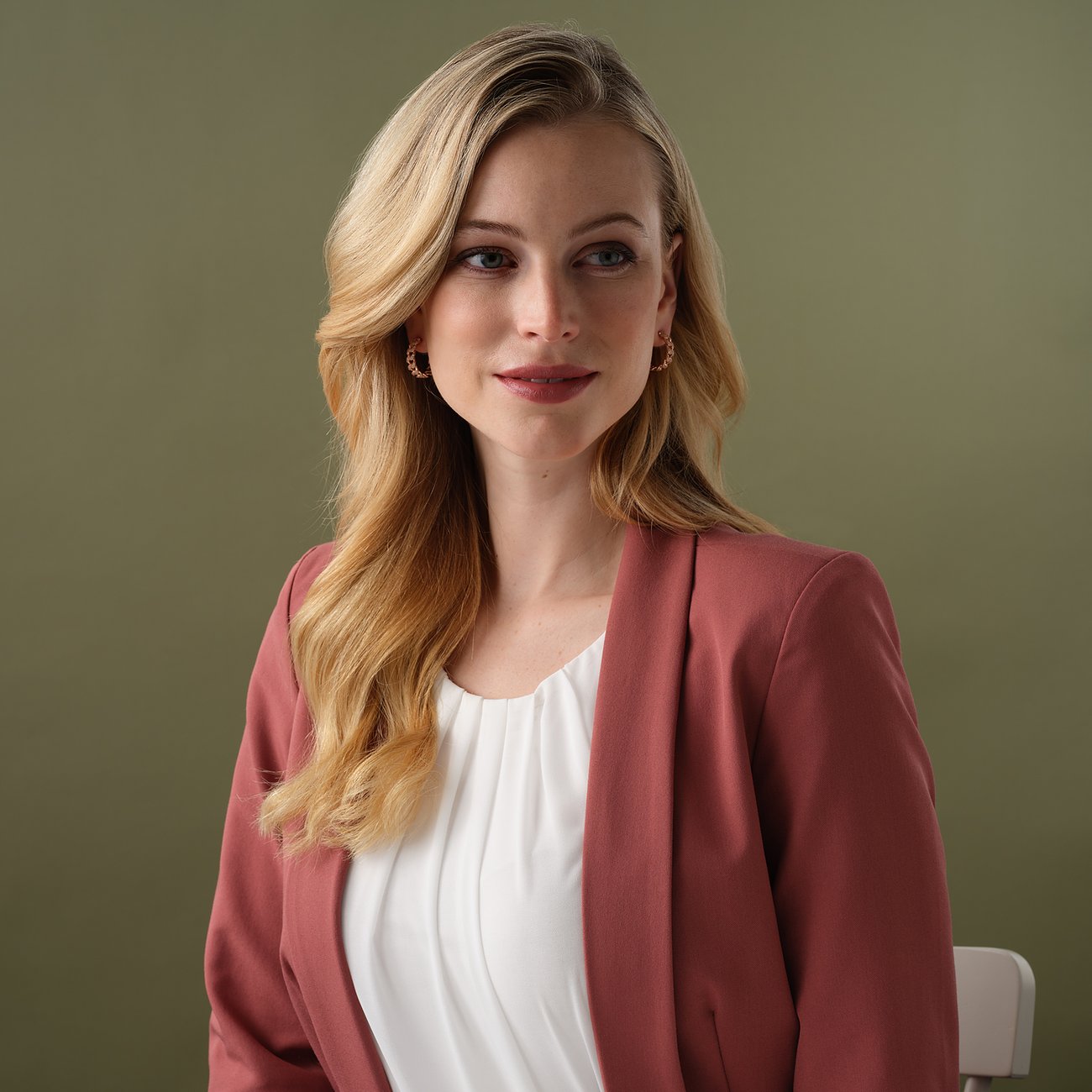 En kvinna med blont hår bär JETTE örhängen i 925 sterlingsilver med färgade zirkoniastenar.