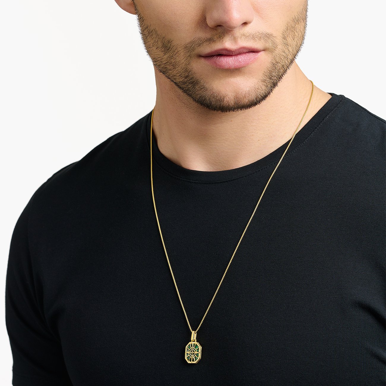 Ein Mann trägt eine Thomas Sabo Silberkette in Goldoptik mit einem Anhänger mit grünem Zirkonia.