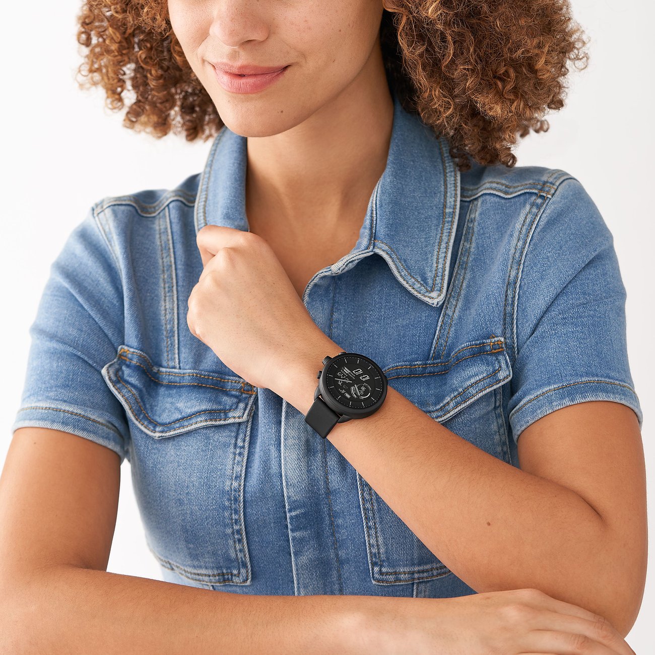 Donna con smartwatch Michael Kors nero in acciaio inossidabile al polso sinistro, indossa un abito di jeans blu.