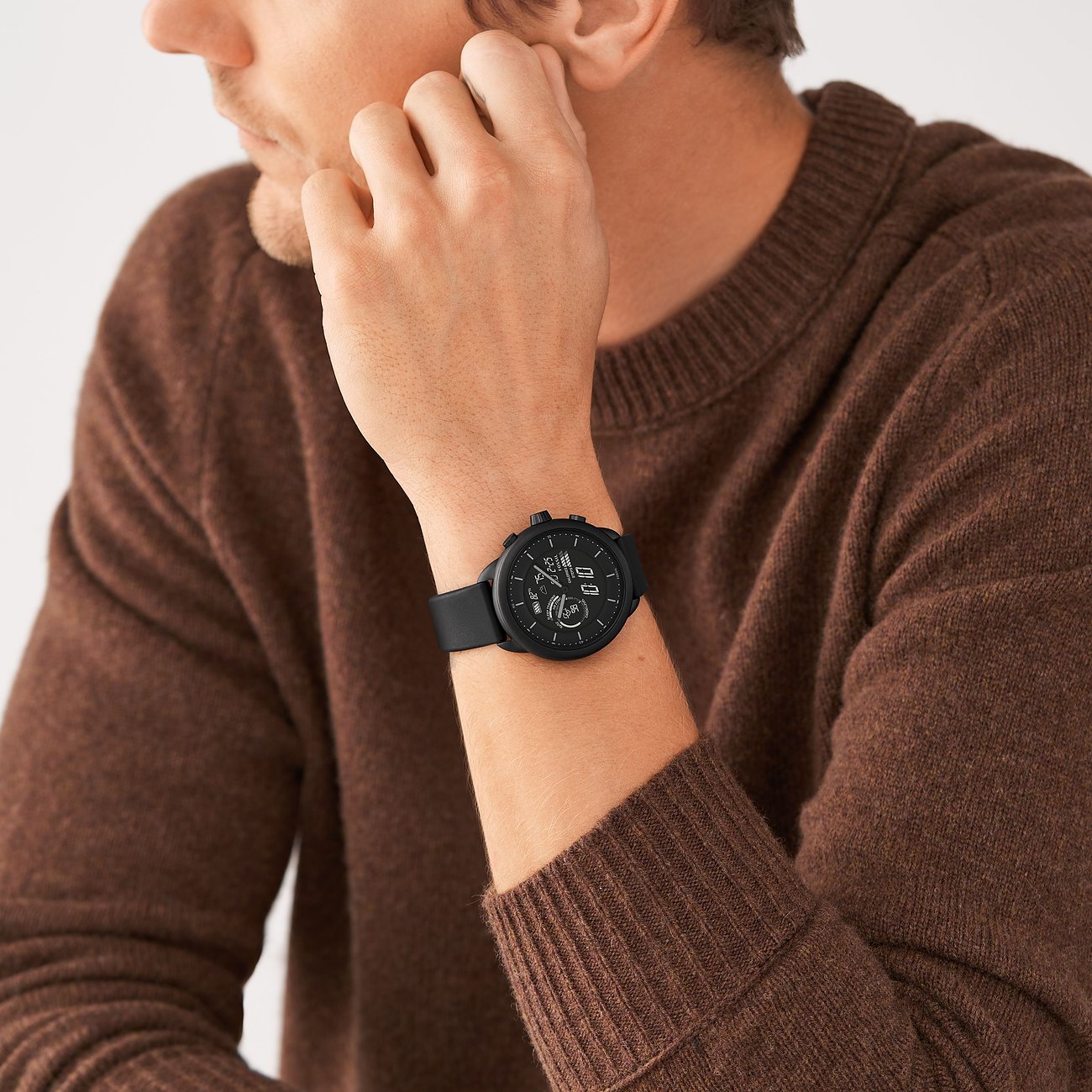 Un uomo indossa uno smartwatch Michael Kors nero in acciaio inossidabile al polso sinistro e si tocca l'orecchio.