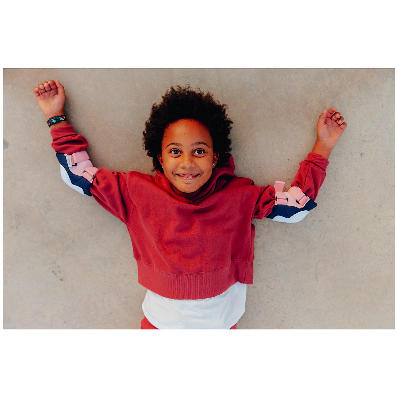 Ett leende barn bär en Flik Flak barn-/ungdomsklocka i plast på vänster handled och ligger på golvet.