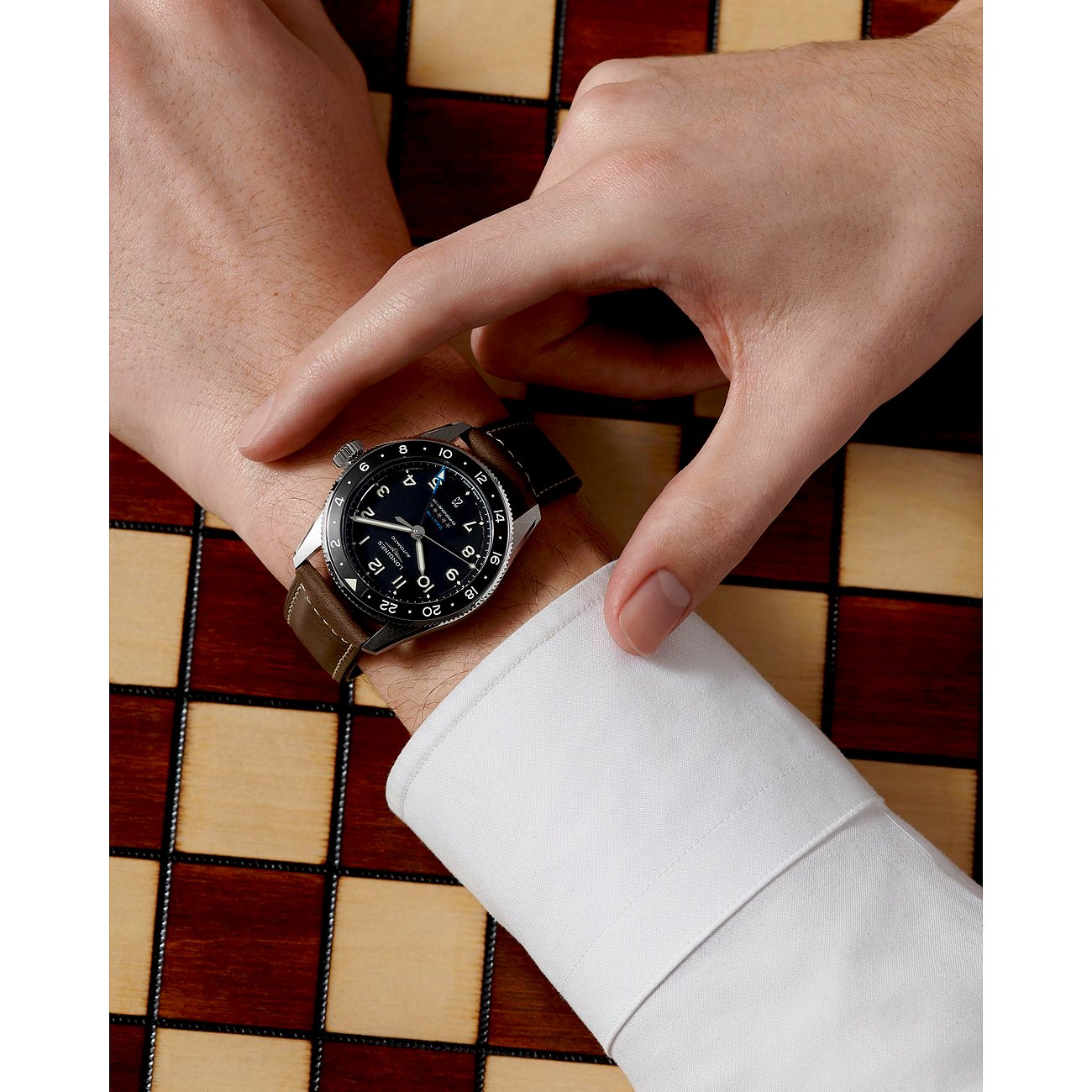 Longines Herrenuhr mit Edelstahlgehäuse, Keramiklünette und braunem Lederarmband.