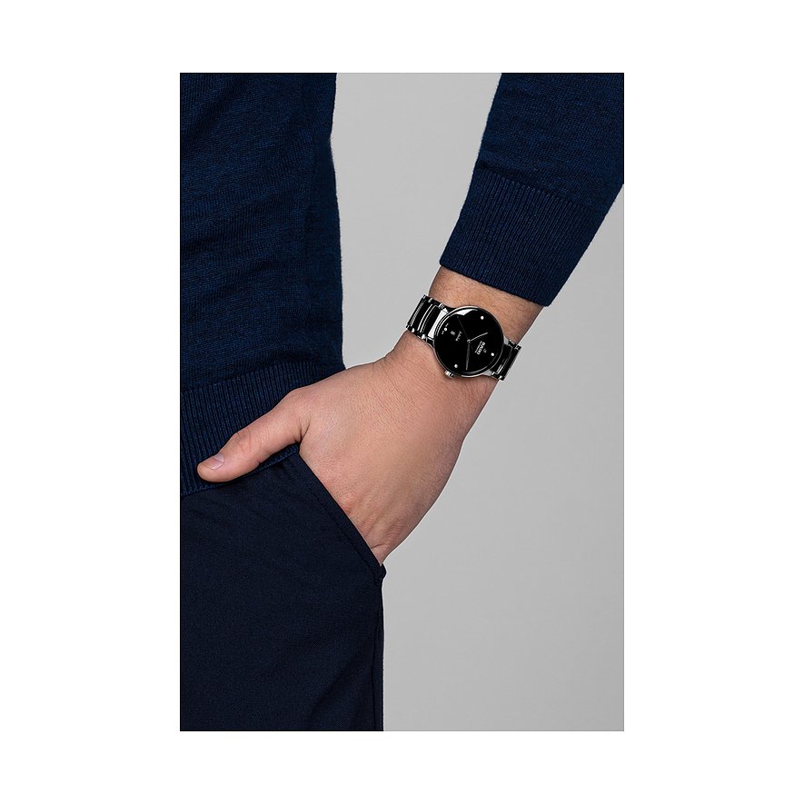 Nahaufnahme einer Rado Unisex-Uhr aus Edelstahl mit Diamanten und schwarzem Zifferblatt, am Handgelenk getragen.
