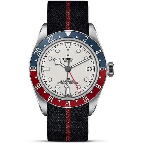 Tudor Herrenuhr mit Edelstahlgehäuse, weißem Zifferblatt und rot-blauer Lünette.